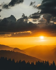 Dramatic sunset over mountains in Samoëns, France, casting golden hues across the sky.