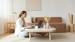 pexels-photo-4492129-4492129 A woman uses a laptop at a coffee table in a cozy living room, embodying a relaxed work-from-home lifestyle.