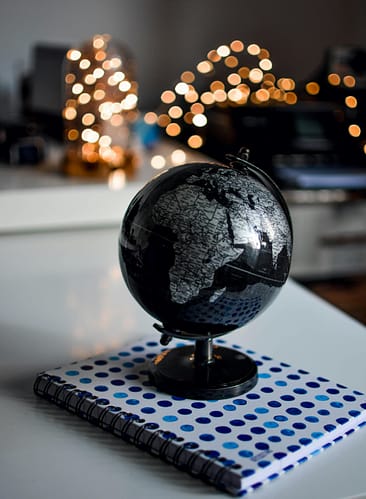 pexels-photo-1236421-1236421 Elegant black globe and notebook against warm bokeh lights, perfect for educational themes.