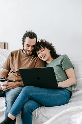 Couple laughing Smiling couple enjoying leisure time on the sofa using a laptop at home and able to rellax